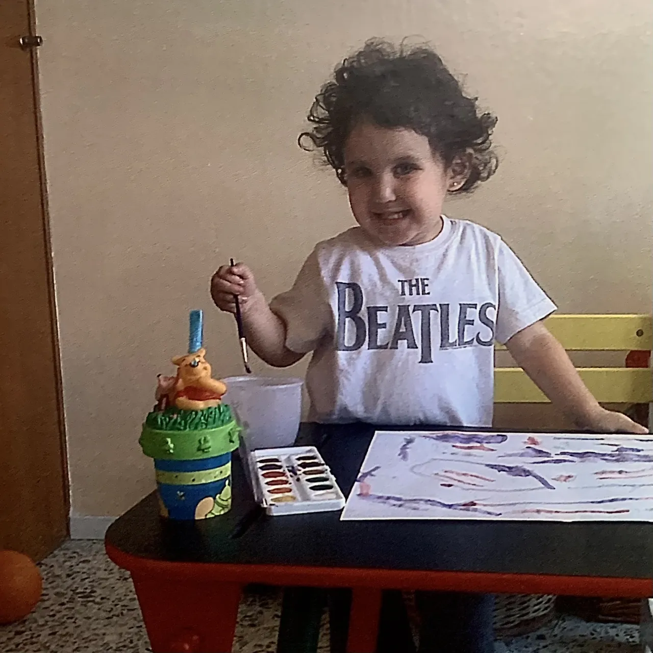 Ximena de niña, pintando con acuarelas en una mesa.